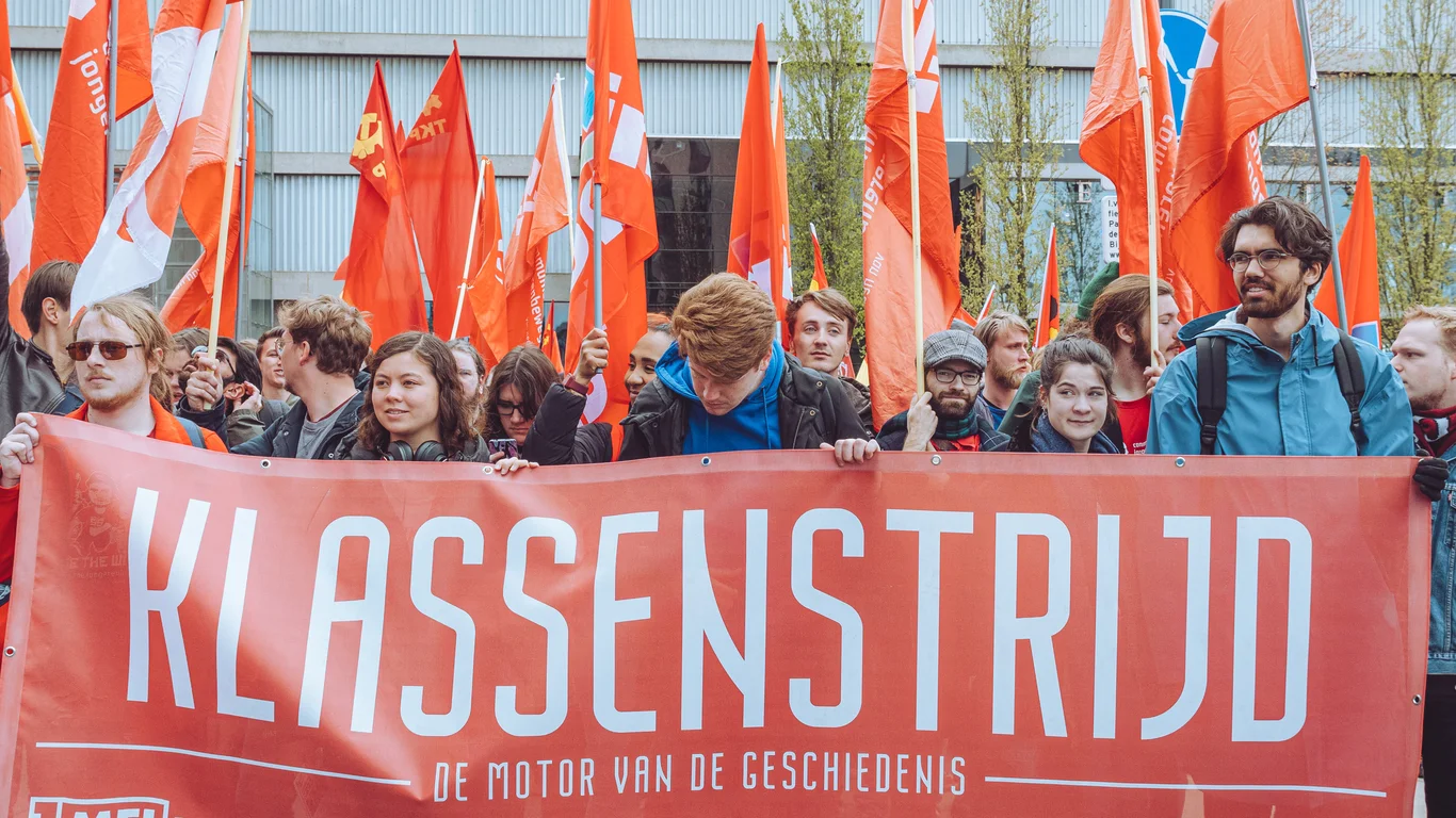 Een foto van demonstrerende communisten met een grote banner waarop staat "Klassenstrijd"