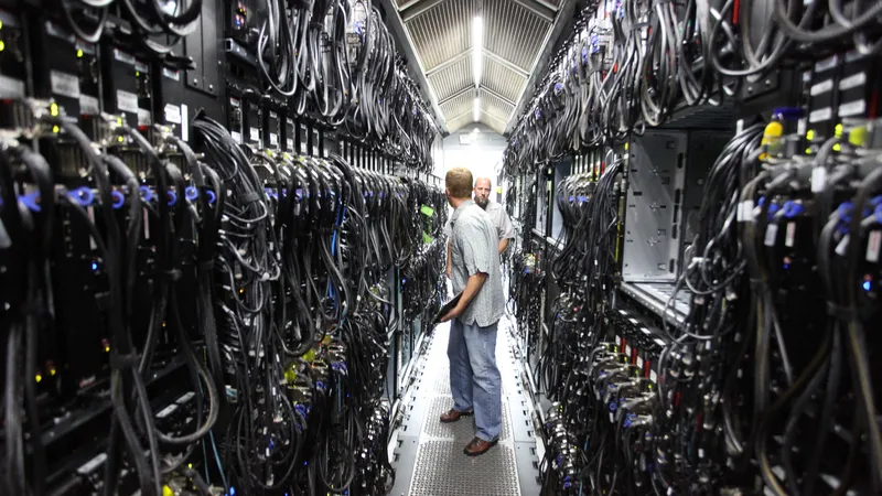 In het gangpad van een datacentrum, tussen een lange rij aan apparaten en kabels