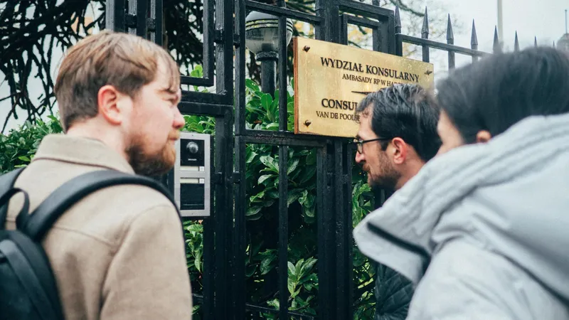 Enkele mensen proberen via de intercom contact te krijgen met de Ambassade van Polen in Den Haag