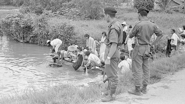 Indonesische soldaten kijken op Sarawak in 1965 toe hoe een groep Chinese arbeiders zich wast. De autoriteiten wilden het gebied ‘beschermen’ tegen communistische invloeden.