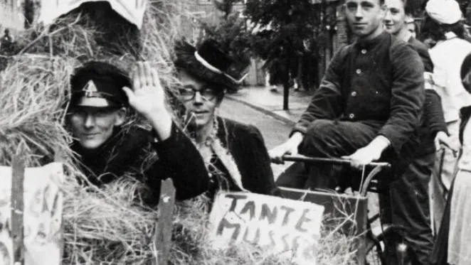 Ries van der Steen, gefotografeerd rijdend op een fiets tijdens een optocht op een buurtfeest, 1945