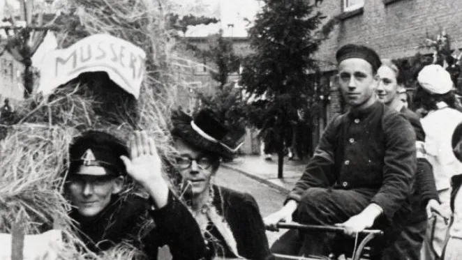 Ries van der Steen, gefotografeerd rijdend op een fiets tijdens een optocht op een buurtfeest, 1945