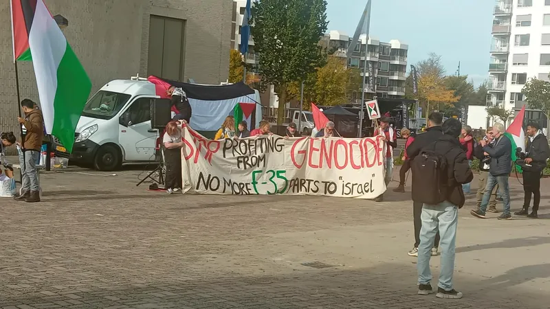 Een groep begint zich te verzamelen voor de demonstratie tegen Fokker. Op een spandoek staat "Stop profiting from genocide: no more F-35 parts to 'Israel'"