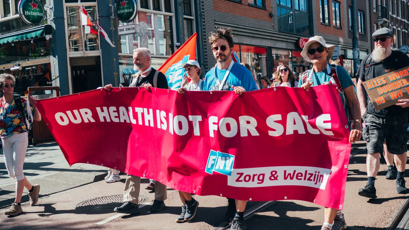 Op een spandoek van FNV Zorg & Welzijn staat: "Our health is not for sale!"