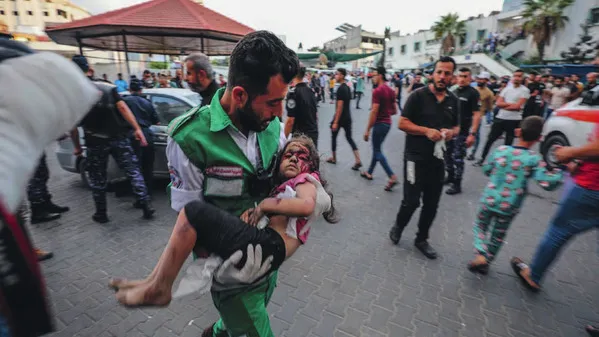 Een Palestijn draagt een gewond kind naar het Al-Shifa-ziekenhuis in Gaza-stad na een Israëlische luchtaanval op 11 oktober 2023.