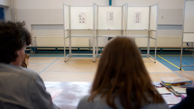 Vrijwilligers zitten aan tafel bij een stembureau