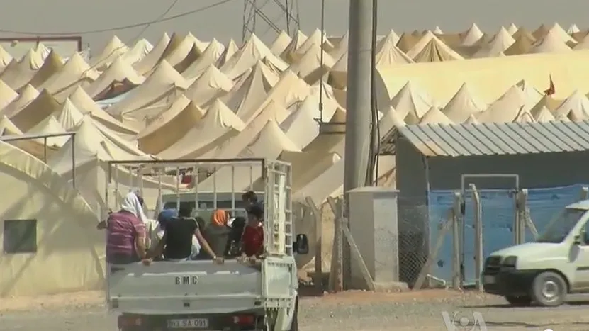 Vluchtelingenkamp in Turkije nabij de Syrische grens, voor vluchtelingen die de burgeroorlog zijn ontvlucht. Op de voorgrond een pick-up truck vol mensen, de achtergrond is bezaaid met tenten.