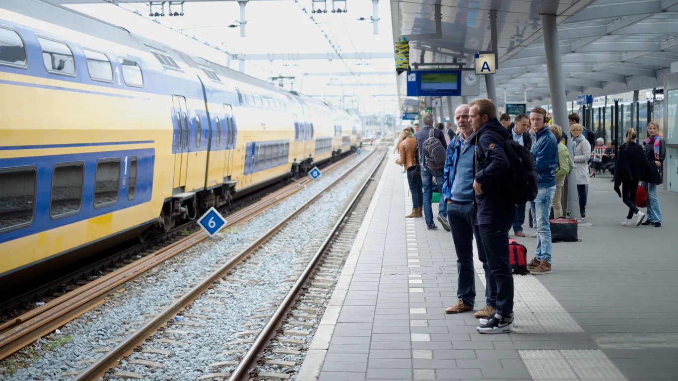 Reizigers staan op het perron te wachten op hun trein