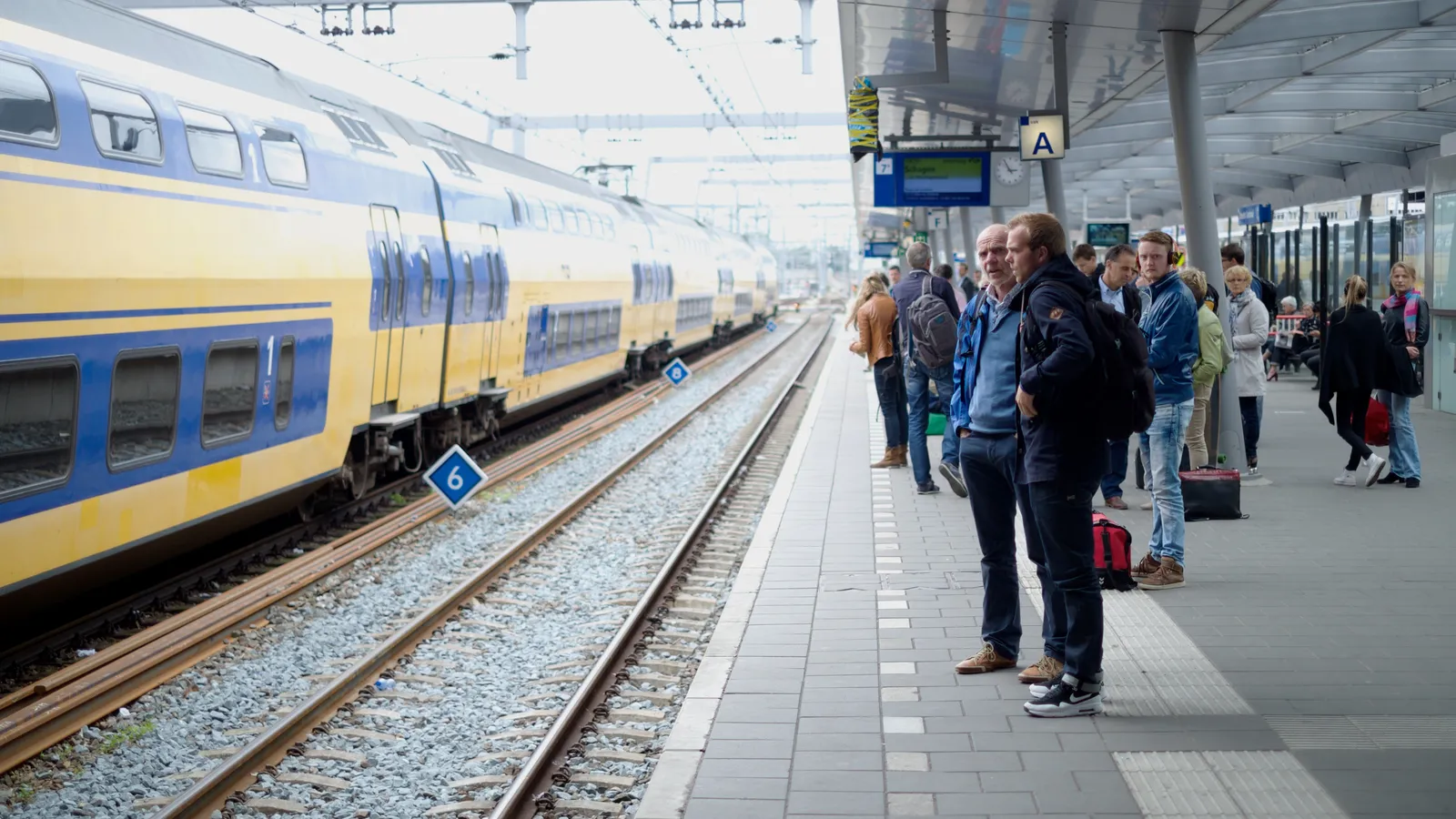 Reizigers staan op het perron te wachten op hun trein