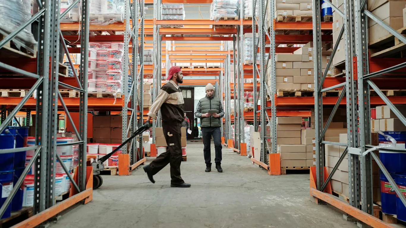 Iemand loopt met een palletwagen door een magazijn