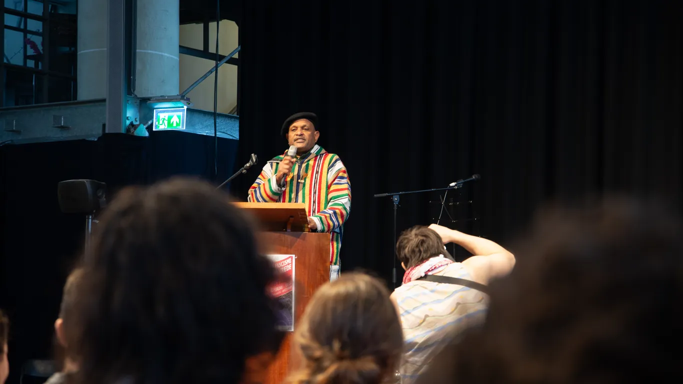 Nasir Omar spreekt op het podium, vanachter een spreekstoel