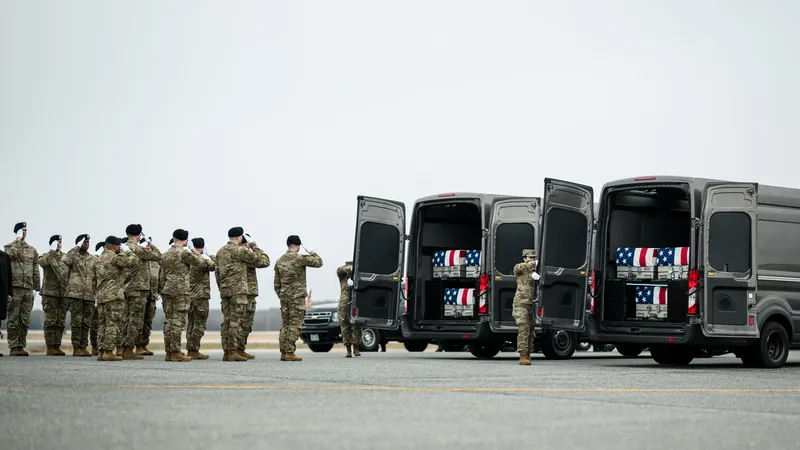 Doodskisten van Amerikaanse soldaten liggen opgestapeld in transportbusjes, terwijl militairen ze salueren